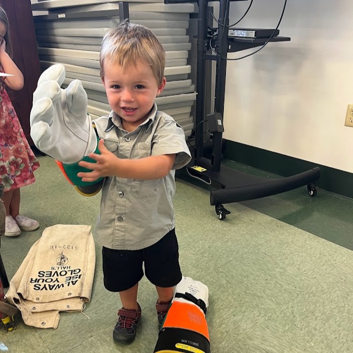 A young boy tries on a pair of lineman gloves.