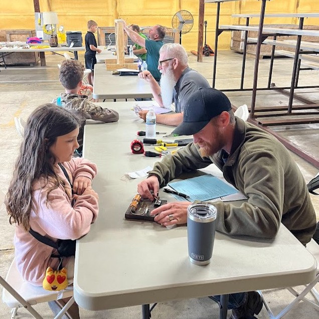 A young girl sits across the table from a Boone Power employee who is judging her 4-H electric project.