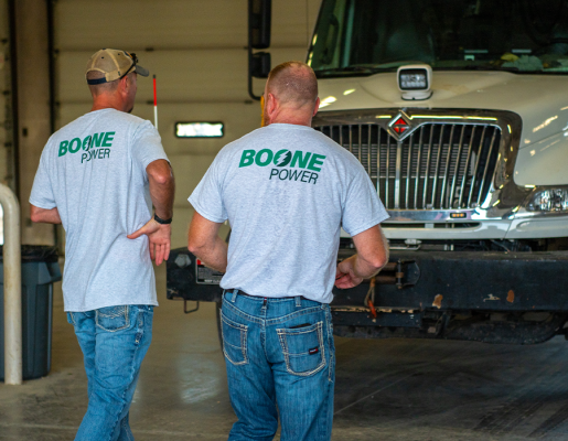 Two Boone Power employees walk through a warehouse in front of a utility truck.